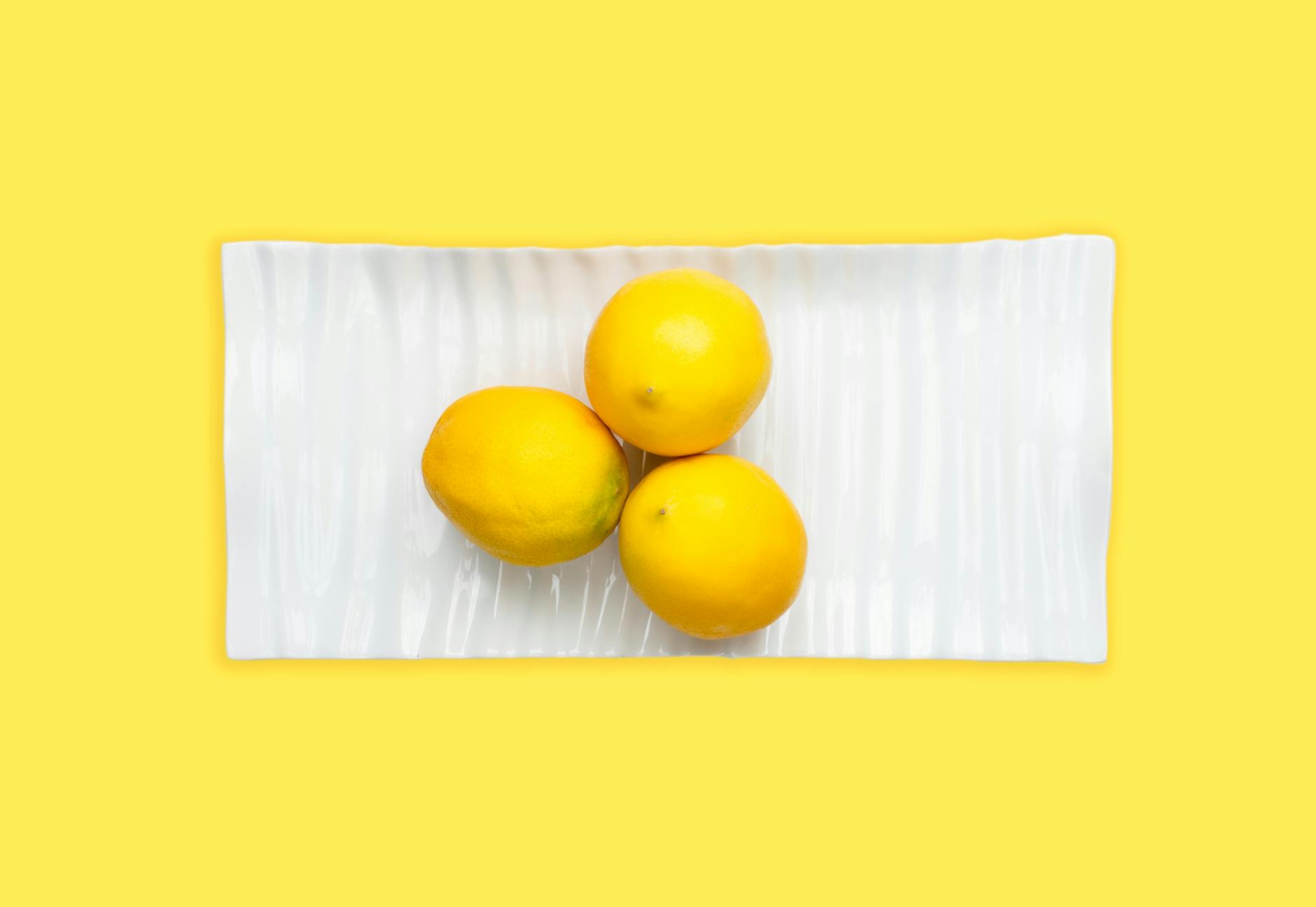 A hand holding a fresh lemon against a bright yellow background, symbolizing the gentle yet powerful nature of the Lem