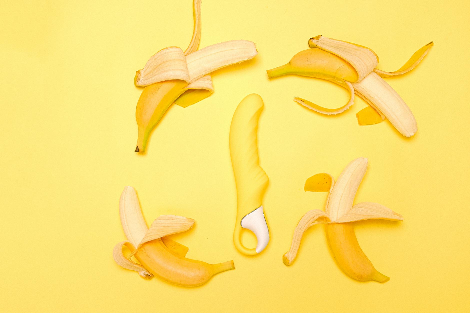 Lemon clitoral vibrator surrounded by fresh lemons on a bright yellow background