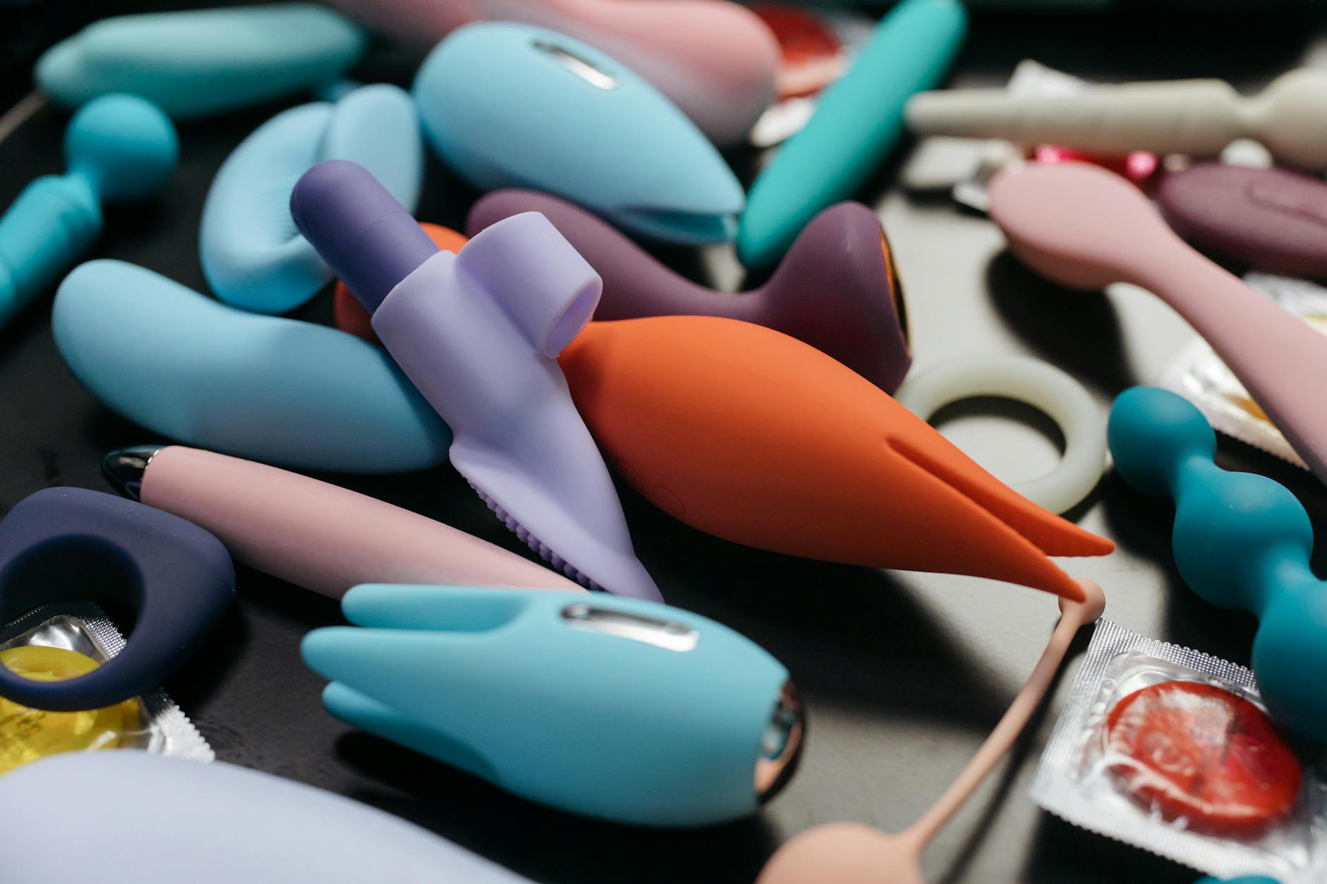 Array of colorful vibrators and intimate wellness devices on a neutral surface