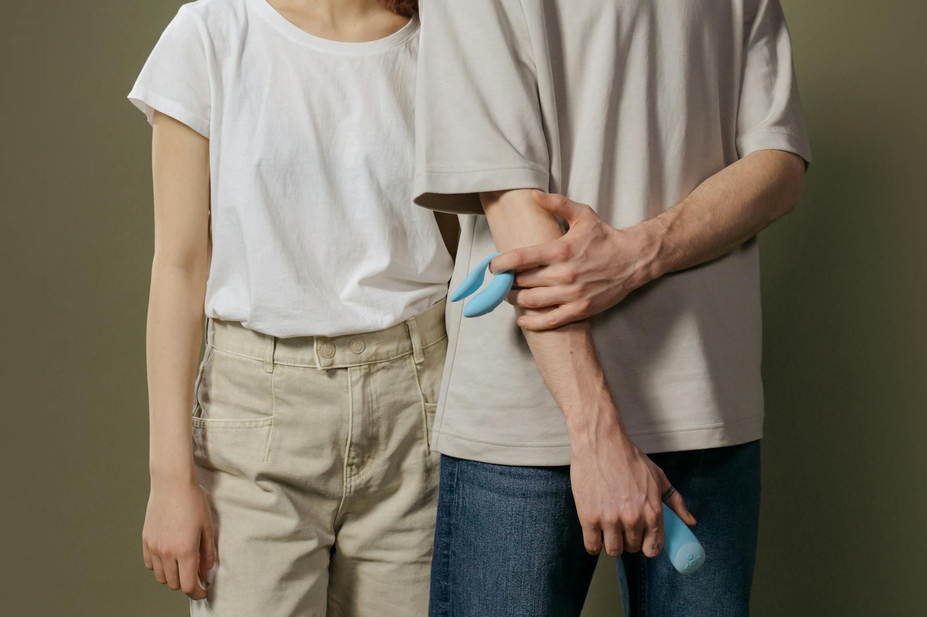 A couple holding a blue vibrator together, discussing intimacy and comfort