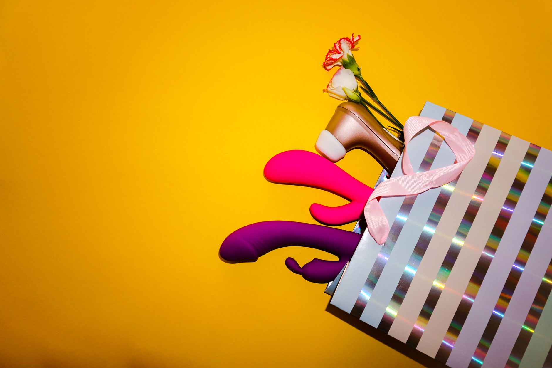 Colorful vibrators and intimate wellness products arranged in a gift display with yellow florals